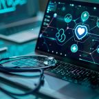 A stethoscope rests on a laptop displaying digital health data.